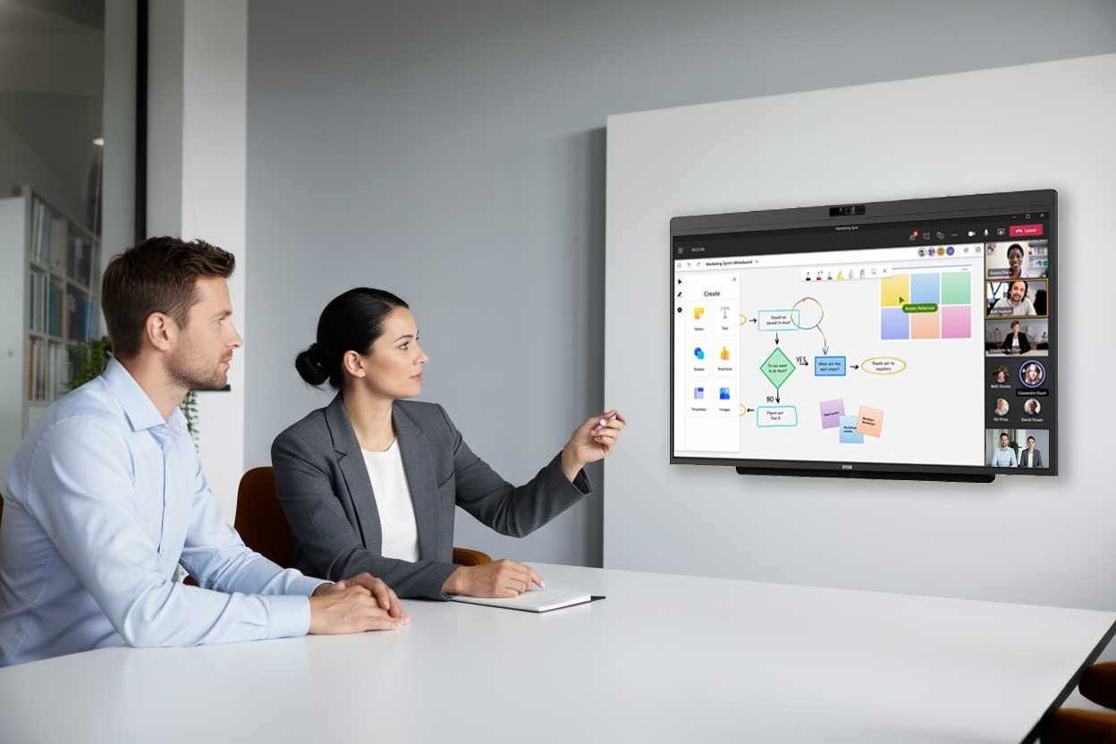 Two people in a small Teams Room using the DTEN D7X AI Board touch display for a Microsoft Teams meeting